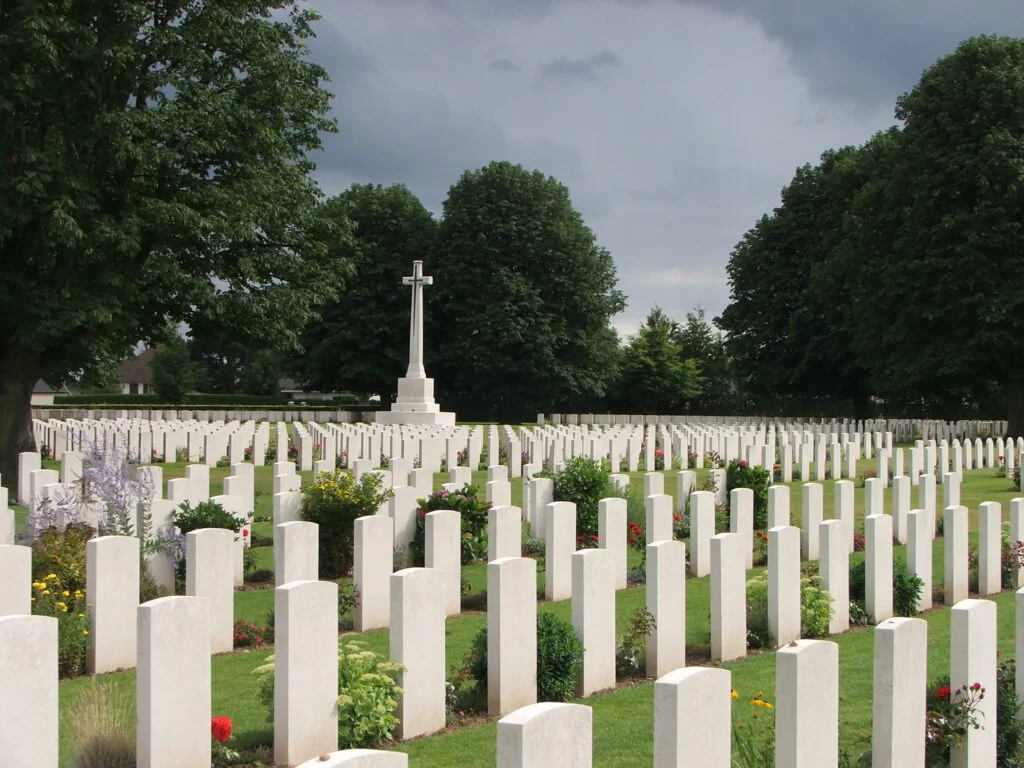 A cemetery with lines of graves left to right and a large cross behind