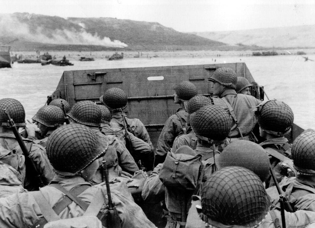 Photo of troops on a small landing craft with land in the distance