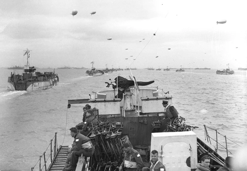 View of the deck of a ship at sea, with others ships visible ahead, in lines to left and right sides